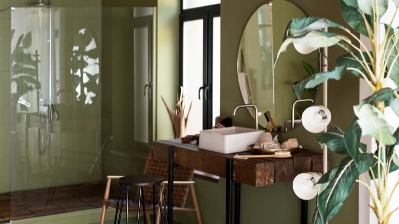 A compact bathroom with white walls and a deep green accent wall behind the vanity.