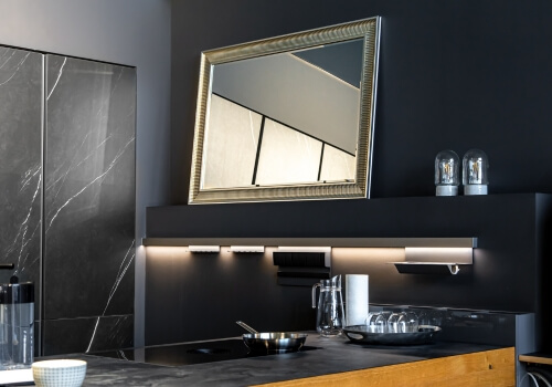 A vanity with white sink, matte black faucet, and brass drawer pulls.